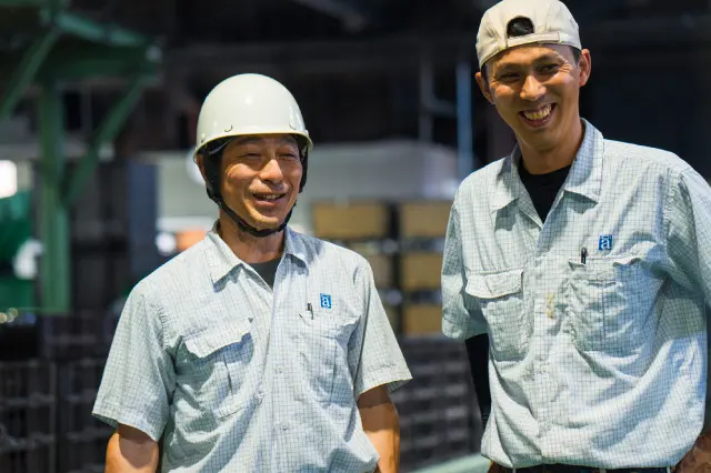 2人の男性社員が笑顔で立っている様子